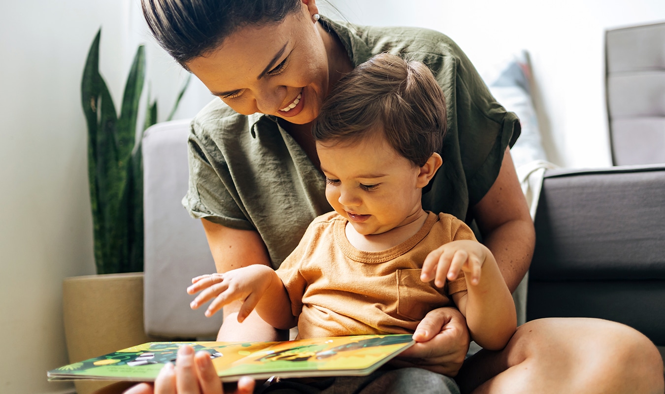 A teacher and child sitting together reading a book.
