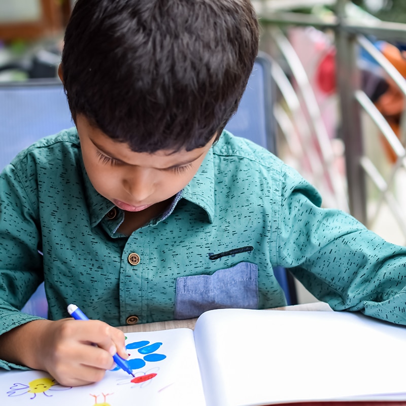 A PreK Student coloring in a book.