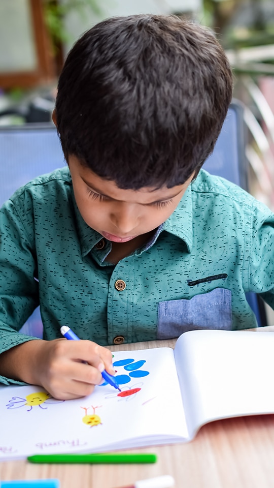 A PreK Student coloring in a book.